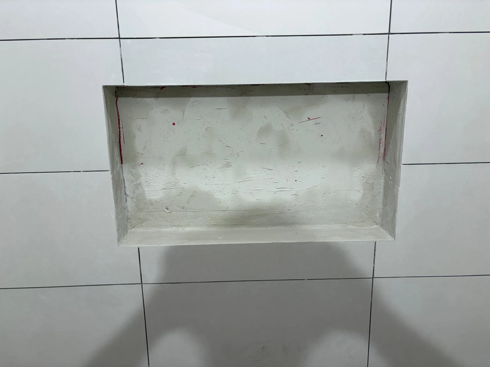 White wall tiles and a shower niche under construction